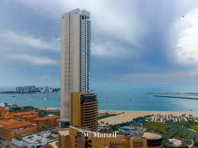 a tall building next to a beach and the ocean at Sea View 2BR in Dubai Marina near Dubai Eye in Dubai