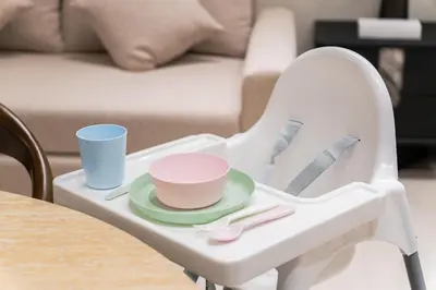 a white high chair with a plate and cups on it at SettlerHomes - JVC Skyline Views - Pool & Gym in Dubai