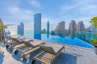 a row of lounge chairs sitting on top of a swimming pool at Bright & Modern 1BR in Dubai Marina in Dubai