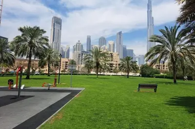 a park with a bench and palm trees in a city at Vogue Business Bay Damac Maison Prive near Burj Khalifa and Dubai Mall, Studio Apartment with Balcony, City and Canal View, Access to all Amenities in Dubai