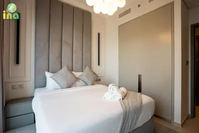 a bedroom with a large white bed with two towels on it at INA HOMES - Modren 2 Bedroom Apartment with Full Burj Khalifa View in Dubai
