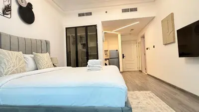 a bedroom with a large white bed and a television at Studio in central location near the Metro in Dubai