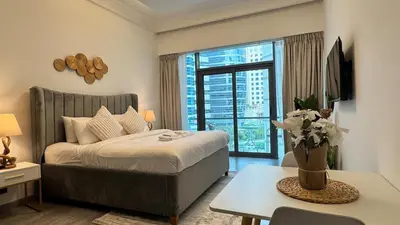 a bedroom with a bed and a table with a vase of flowers at Studio in central location with Balcony nearby Metro in Dubai
