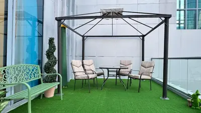 a table and chairs on a balcony with green grass at Studio centrally located with a huge private balcony in Dubai