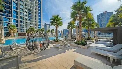 a patio with a swing and a pool with palm trees at Vogue Business Bay Damac Maison Prive near Burj Khalifa and Dubai Mall, Studio Apartment with Balcony, Pool and City View, Access to all Amenities in Dubai