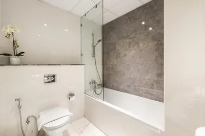 a white bathroom with a shower and a toilet at Stunning 1BR at Noora Tower, Al Habtoor City in Dubai