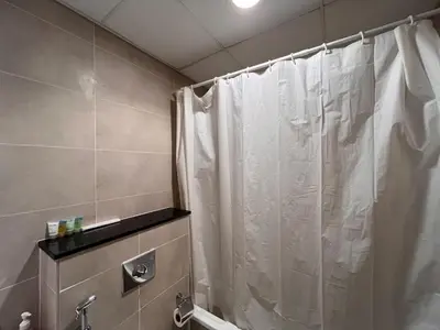 a bathroom with a shower with a white shower curtain at Modern 1BR Apartment Golf View Gym Pool in Dubai