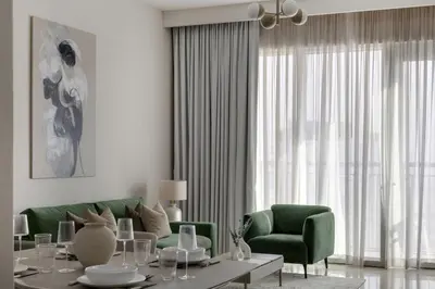 a living room with a green couch and a table at 30th Floor Creek Harbour 1 Bedroom Apartment in Dubai