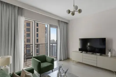 a living room with a television and a green chair at 30th Floor Creek Harbour 1 Bedroom Apartment in Dubai