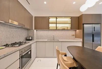 a kitchen with white cabinets and a wooden table at Grand Bleu by Elie Saab Residency, Private Beach - Dubai Harbour - 2BR in Dubai