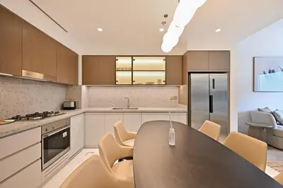 a kitchen with a large wooden table and chairs at Grand Bleu by Elie Saab Residency, Private Beach - Dubai Harbour - 2BR in Dubai