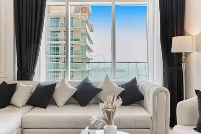 a living room with a couch and a large window at PS5- Designer 2BR with Private Beach, Dubai Eye, Palm in Dubai