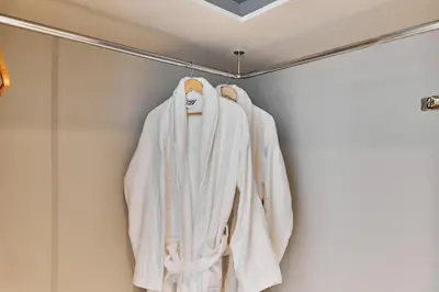 a white robe hanging on a rack in a bathroom at PS5- Designer 2BR with Private Beach, Dubai Eye, Palm in Dubai