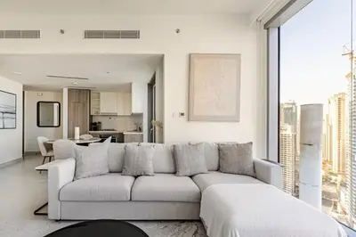 a living room with a white couch and a kitchen at Oshima LIV Marina 1BR Marina View in Dubai