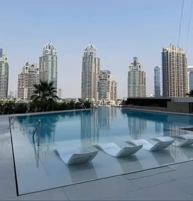 a swimming pool with white chairs in front of a city at Oshima LIV Marina 1BR Marina View in Dubai
