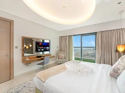 a bedroom with a bed and a desk and a television at Sky-high 1Br Apartment Sleeps 4 in Damac Paramount in Dubai