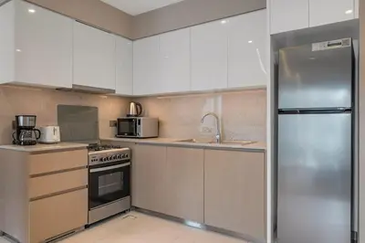 a kitchen with white cabinets and a stainless steel refrigerator at Downtown Suite Trendy 1BR -Dubai Mall Access in Dubai