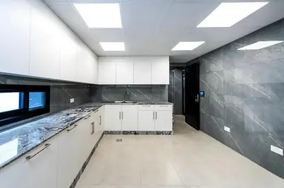 a kitchen with white cabinets and a black wall at Luxurious 4 Bedroom Villa In Emirates Hills in Dubai