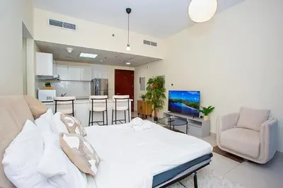 a bedroom with a white bed and a kitchen at Cozy 2 Bedroom Apartment with Balcony Near JBR Beach in Dubai