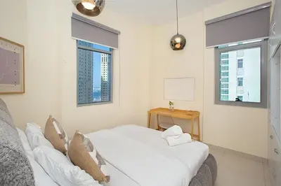 a white room with a bed and two windows at 2 Bedroom Apartment JBR Skyline with Balcony in Dubai