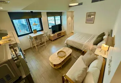 a living room with a couch and a bed and a table at Warm Minimalist Studio , Walk to Metro , Pool, Gym in Dubai