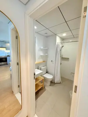 a bathroom with a toilet and a sink and a mirror at Warm Minimalist Studio , Walk to Metro , Pool, Gym in Dubai
