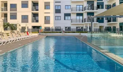 a swimming pool in front of a apartment building at Warm Minimalist Studio , Walk to Metro , Pool, Gym in Dubai
