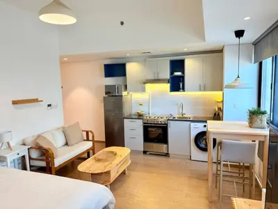 a kitchen and living room with a couch and a table at Warm Minimalist Studio , Walk to Metro , Pool, Gym in Dubai