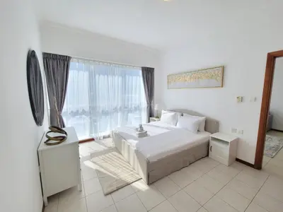 a bedroom with a white bed and a large window at One Bedroom Apartment in Mag 214, JLT in Dubai