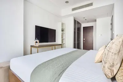 a white bedroom with a large bed and a flat screen tv at Frank Porter - Dubai Marina Mall Hotel in Dubai