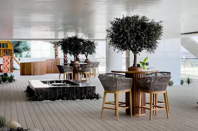 a row of tables with potted trees in a room at Luxury 1BR Duplex on the Canal Business Bay in Dubai