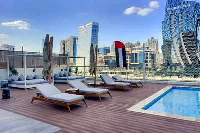 a rooftop patio with chairs and a pool on a building at Luxury 1BR Duplex on the Canal Business Bay in Dubai