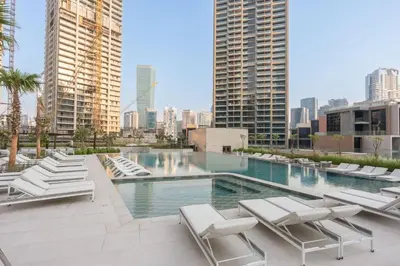 a swimming pool with lounge chairs and a city skyline at Stayshort - 1 Bedroom in Business Bay with Canal Views that Sleeps 4 in Dubai
