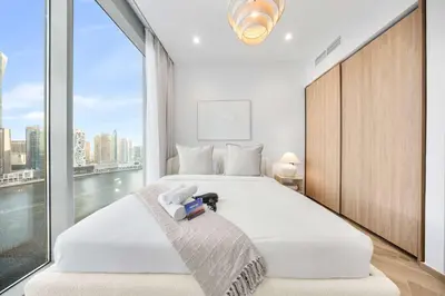 a bedroom with a large white bed with a large window at Stayshort - 1 Bedroom in Business Bay with Canal Views that Sleeps 4 in Dubai