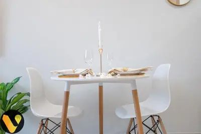 a white dining room table with white chairs at Vogue Sports City Hera Tower Near First Avenue Mall, Studio Apartment with Balcony, Canal and City View, Access to all Amenities in Dubai