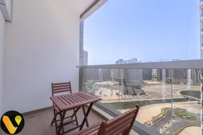 a balcony with a wooden table and chairs on a balcony at Vogue Sports City Hera Tower Near First Avenue Mall, Studio Apartment with Balcony, Canal and City View, Access to all Amenities in Dubai
