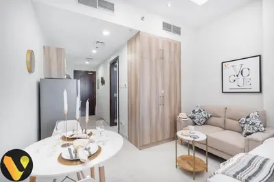 a white living room with a table and a couch at Vogue Sports City Hera Tower Near First Avenue Mall, Studio Apartment with Balcony, Canal and City View, Access to all Amenities in Dubai