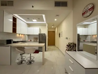 a kitchen with white cabinets and a table and a clock at Chic Studio in Dar Al Jawhara Residence in Dubai