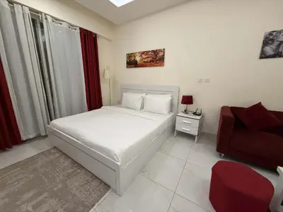 a bedroom with a white bed and a red chair at Chic Studio in Dar Al Jawhara Residence in Dubai
