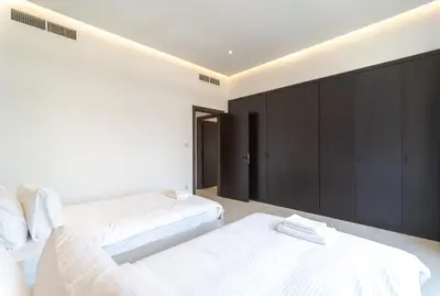 two beds in a room with black cabinets at Stunning 3BDR in Al Sidir Greens in Dubai