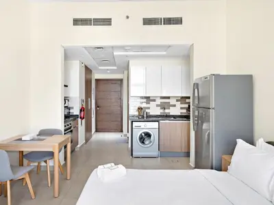 a kitchen and living room with a refrigerator and a table at Modern Studio In Al-Furjan close to Metro-15 in Dubai