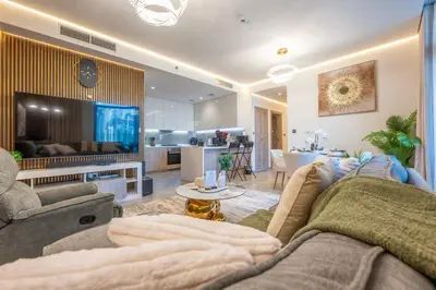 a living room with a couch and a tv and a kitchen at 2 Bedroom in Peninsula with Burj View in Dubai