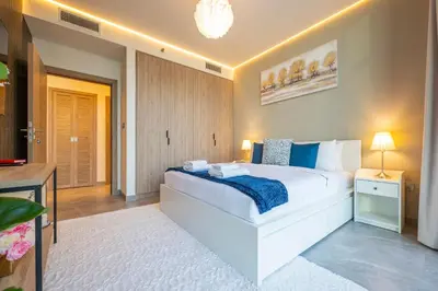 a bedroom with a large white bed and a television at 2 Bedroom in Peninsula with Burj View in Dubai