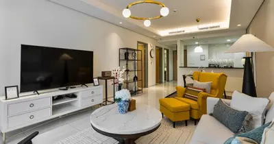 a living room with a large television and yellow chairs at Burj View 2BHK Downtown Infinity Pool in Dubai