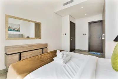 a bedroom with a large white bed with a mirror at Beautiful 2BR at Majestique Residence Dubai South in Dubai
