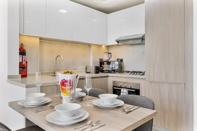 a kitchen with a wooden table with plates and bowls at Beautiful 2BR at Majestique Residence Dubai South in Dubai