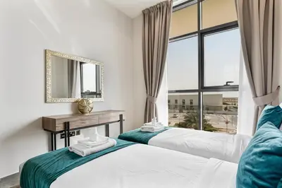 two beds in a room with a mirror and a window at Beautiful 2BR at Majestique Residence Dubai South in Dubai