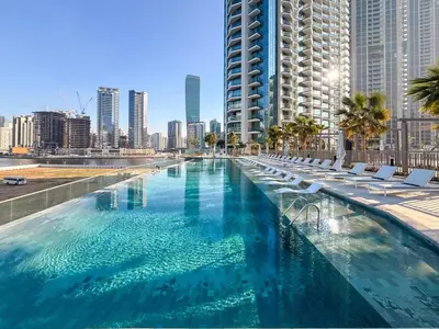 a large swimming pool with lounge chairs and a city at GuestReady - 1BR l Burj Khalifa View in Dubai