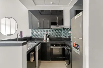a kitchen with stainless steel appliances and black cabinets at Silkhaus Studio Stay in Dubai Marina - Botanica in Dubai