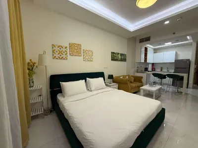 a bedroom with a large bed and a living room at Refined Studio at Dar Al Jawhara in Dubai